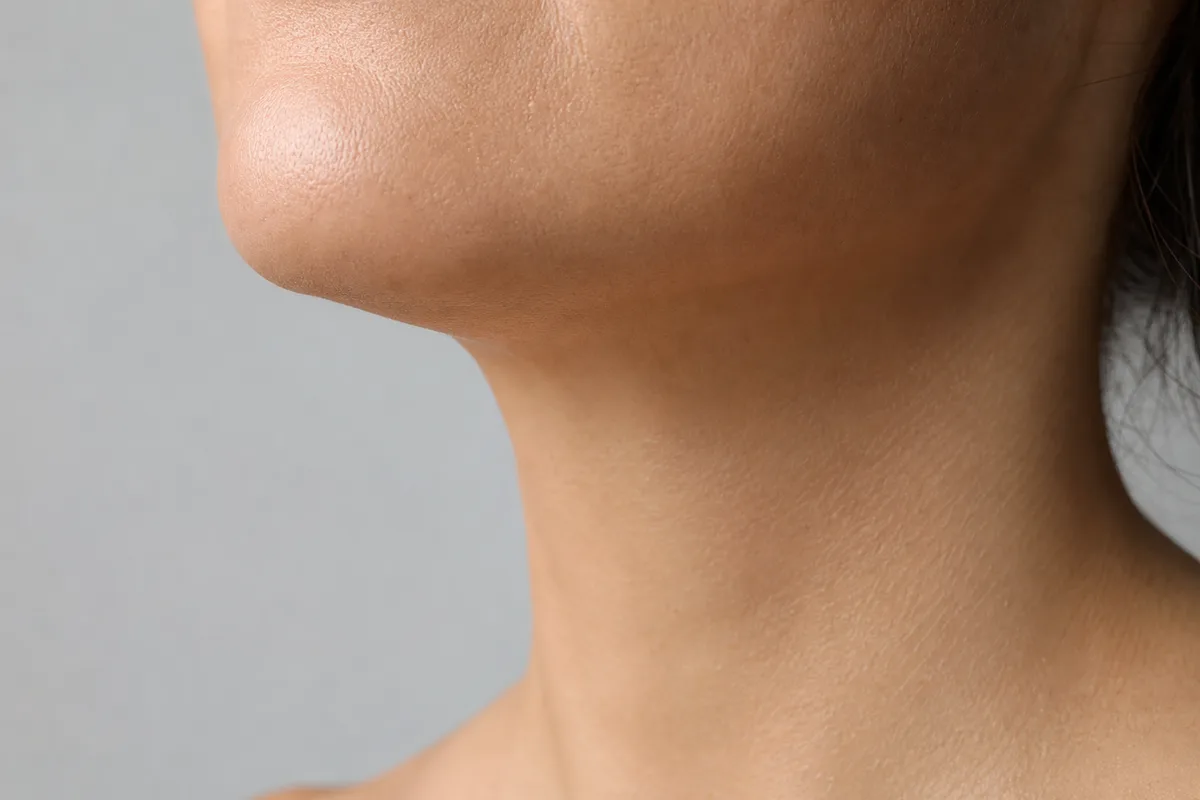 Gros plan sur le bas d un visage feminin de profil, machoire et cou, lumiere douce de studio, peau nette